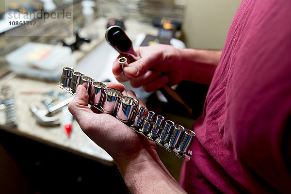 Männerhände wählen Steckschlüssel zur Reparatur des Badezimmers