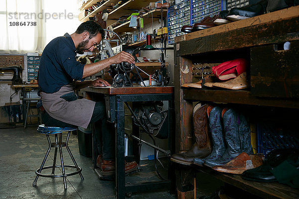 Männlicher Schuster in traditioneller Schuhwerkstatt an der Nähmaschine