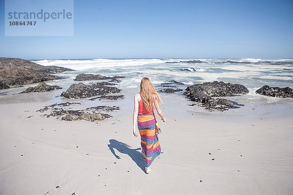 Rückansicht eines Mädchens mit Sarong  das am Strand spazieren geht  Kapstadt  Südafrika