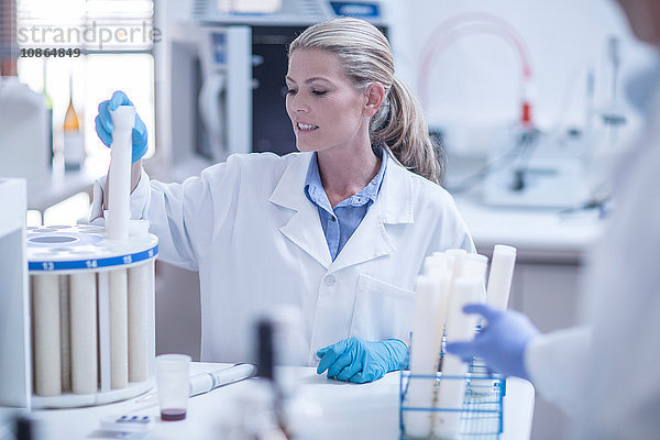 Mittlere erwachsene Frau im Labor beim Einführen des Reagenzröhrchens in die Schale