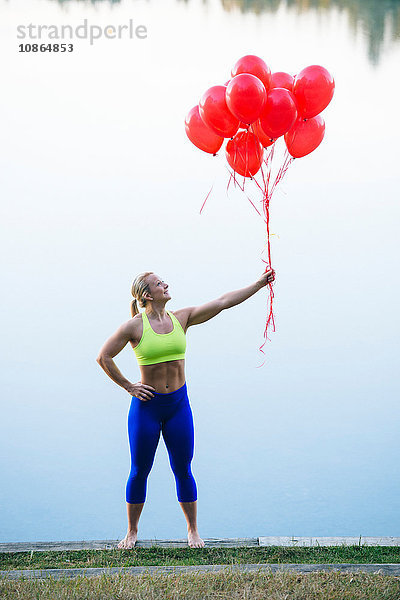 Frau hält einen Haufen roter Luftballons