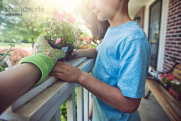 Hand tragender Gartenhandschuh  der Pflanzen an Jungen und Mädchen weitergibt