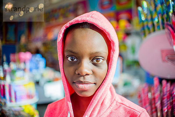 Porträt einer Teenagerin vor einem Süßwarenstand mit rosa Kapuzenpulli  Brooklyn  USA