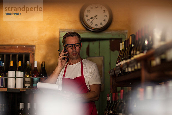 Mann  der in einer Weinhandlung arbeitet  telefoniert