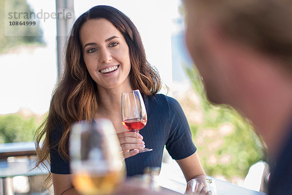Frau hält Weinglas und sieht Freund lächelnd an