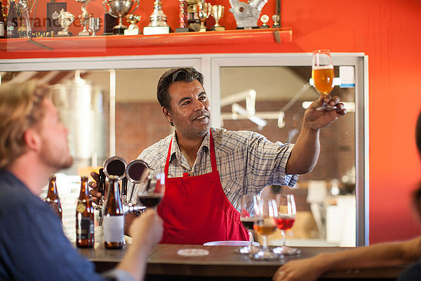 Barkeeper in Gaststätte hält Bierglas lächelnd in der Hand
