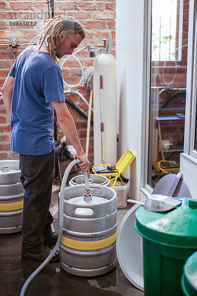 Mann reinigt Bierfässer in Kleinbrauerei