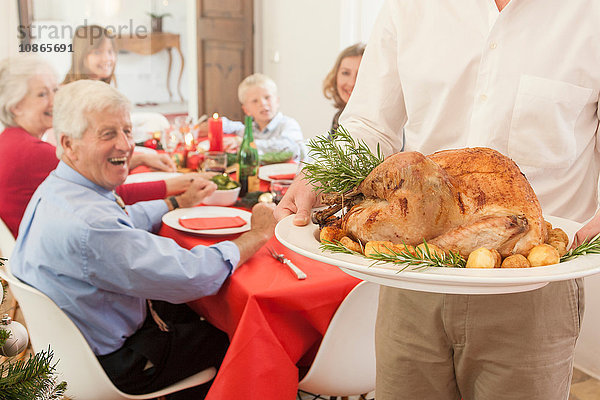 Mann serviert der Familie beim Weihnachtsessen Truthahn