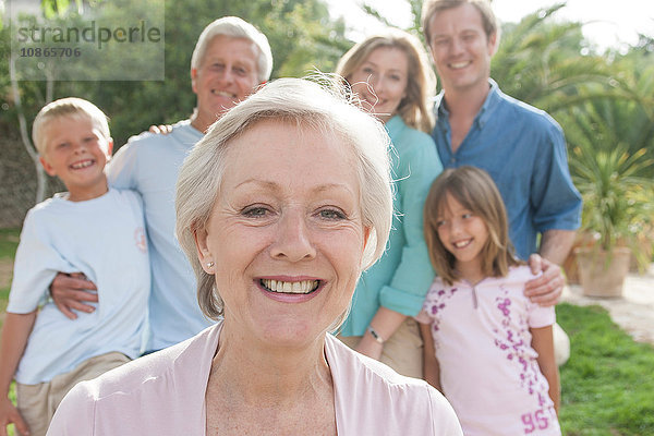 Porträt einer älteren Frau vor der Familie  die lächelnd in die Kamera schaut