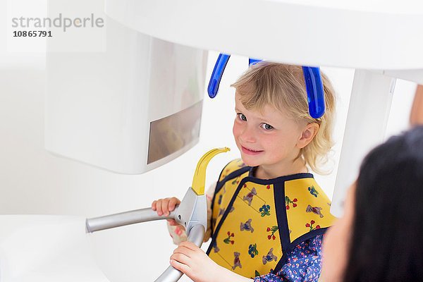 Hochwinkelansicht eines Mädchens in einem Röntgengerät mit lächelnder Zahnuntersuchung