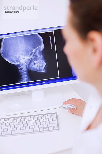 Seitenansicht des Zahnarztes beim Betrachten des Röntgenbildes auf dem Computerbildschirm