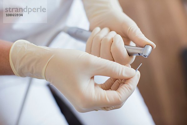 Schrägansicht einer Zahnarzthelferin mit Schutzhandschuhen bei der Vorbereitung der zahnärztlichen Ausrüstung