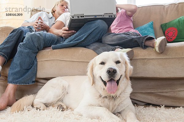 Familie mit Laptop auf der Couch  Haushund im Vordergrund