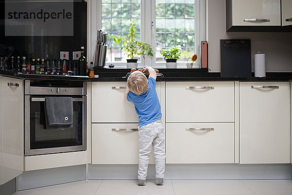 Junge in der Küche  nach frisch gebackenen Muffins greifend  Rückansicht
