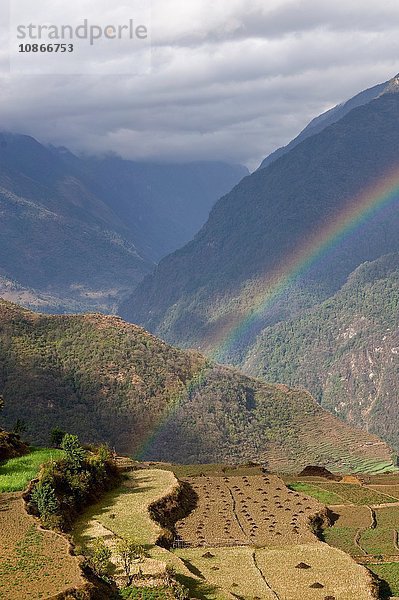 Regenbogen über ländlichem Bergtal