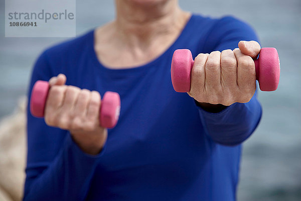 Reife Frau im Freien  die mit Handgewichten trainiert