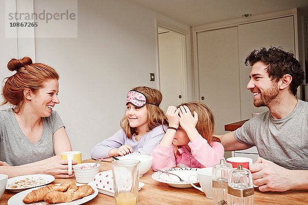 Mittlere erwachsene Eltern am Frühstückstisch mit zwei Töchtern