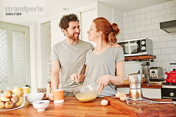 Mittelgroßes erwachsenes Paar verquirlt zum Frühstück Eier an der Küchentheke