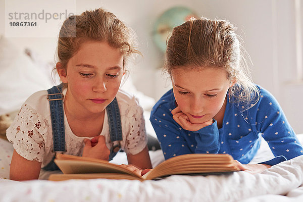 Zwei Schwestern liegen im Bett und lesen ein Buch