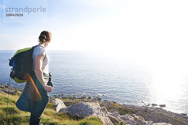 Wanderer mit Rucksack auf einer Klippe mit Blick auf den Ozean  Portland  UK