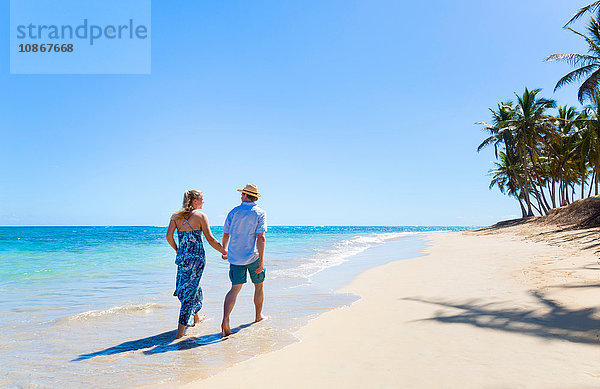 Rückansicht eines erwachsenen Paares beim Strandspaziergang  Dominikanische Republik  Karibik