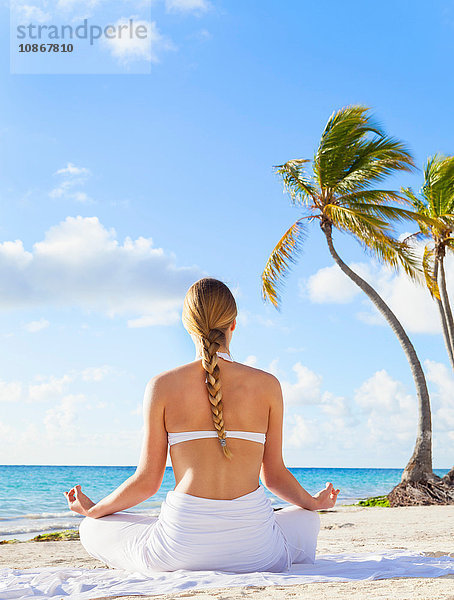 Rückansicht einer jungen Frau  die am Strand eine Yogalotus-Pose einnimmt  Dominikanische Republik  Karibik