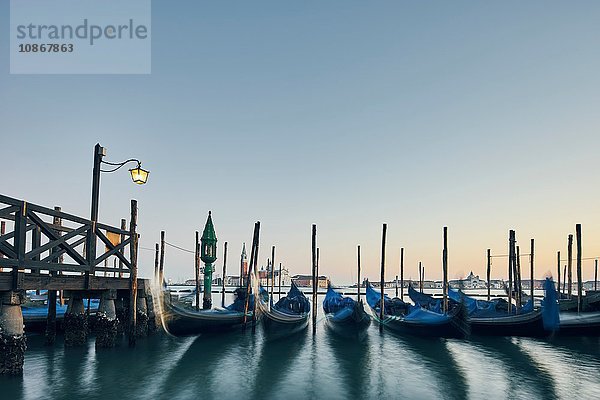 Reihen vertäuter Gondeln am Wasser in der Abenddämmerung  Venedig  Italien