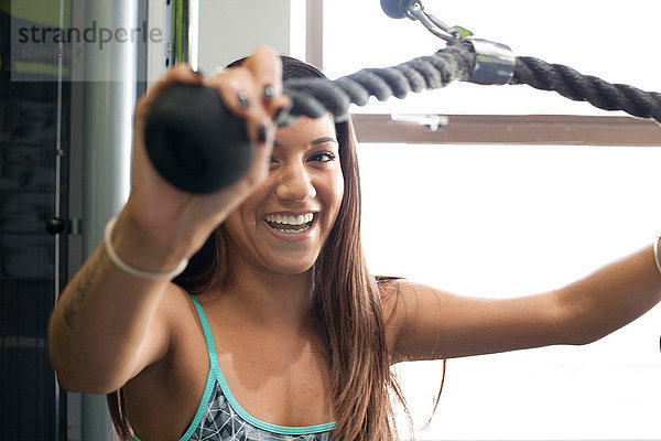 Frau im Fitnessstudio mit Trainingsgerät  die lächelnd in die Kamera schaut