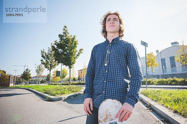 Porträt eines jungen männlichen Skateboardfahrers auf dem Bürgersteig