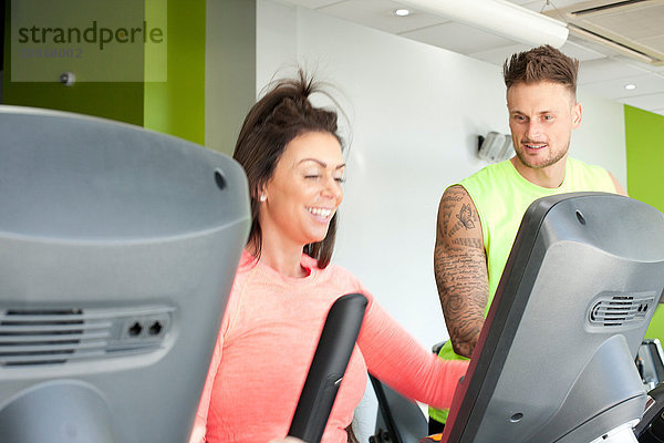 Mann und Frau im Fitnessstudio mit lächelnder Trainingsmaschine