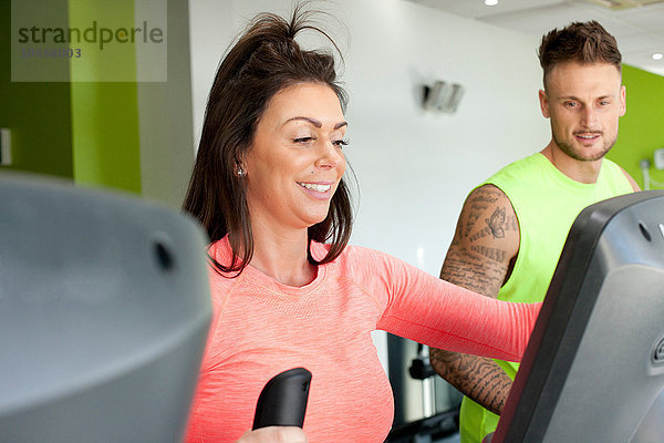 Mann und Frau im Fitnessstudio mit lächelnder Trainingsmaschine