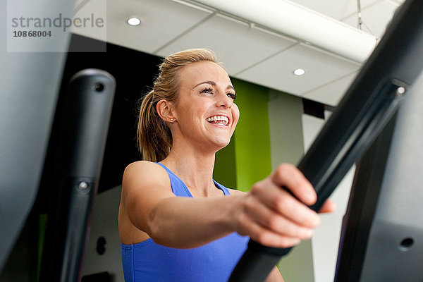 Frau im Fitnessstudio mit lächelnder Trainingsmaschine