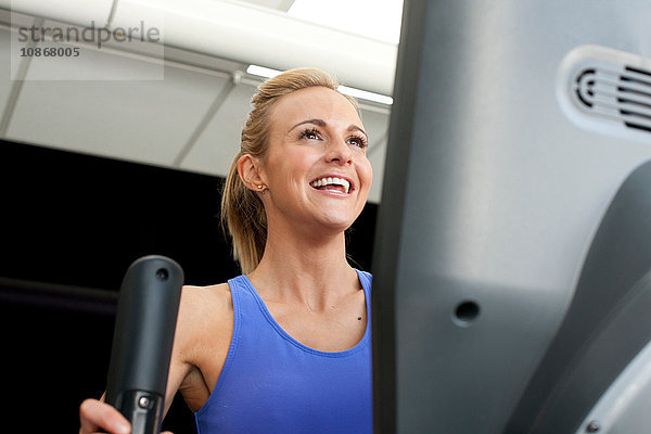 Frau im Fitnessstudio mit lächelnder Trainingsmaschine