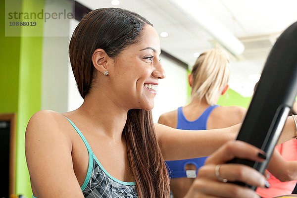 Frau im Fitnessstudio mit Trainingsgeräten  die lächelnd wegschauen