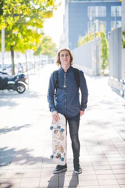 Porträt eines selbstbewussten jungen Skateboardfahrers auf dem Bürgersteig