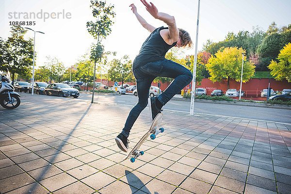 Junger männlicher Skateboarder beim Skateboarden auf dem Bürgersteig