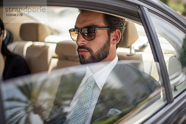 Junger Geschäftsmann mit Sonnenbrille auf dem Rücksitz eines Autos  Dubai  Vereinigte Arabische Emirate