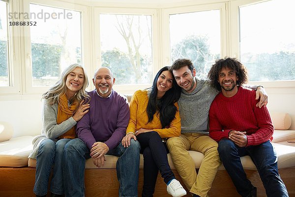 Familie nebeneinander auf dem Fenstersitz mit Blick in die Kamera lächelnd