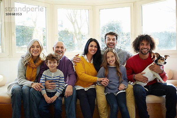 Mehrgenerationen-Familie und Hund auf dem Fenstersitz  der lächelnd in die Kamera schaut