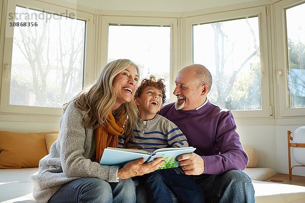 Großeltern auf Fenstersitz Lesebuch mit Enkel  lächelnd