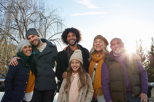 Mehrgenerationen-Familie  die Mäntel und Strickmützen trägt und auf das Lächeln der Familie schaut