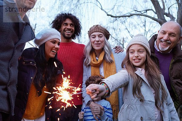 Mädchen mit Mehrgenerationen-Familie hält Wunderkerze lächelnd