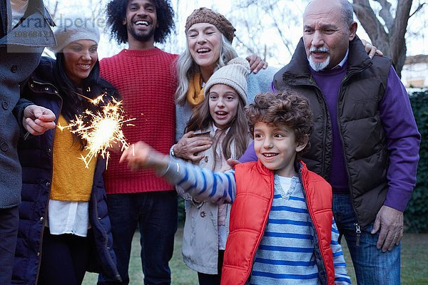 Junge mit Mehrgenerationen-Familie hält Wunderkerze lächelnd