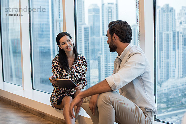 Geschäftsfrau und Mann sitzen am Fenster mit Blick auf einen Wolkenkratzer  Dubai  Vereinigte Arabische Emirate