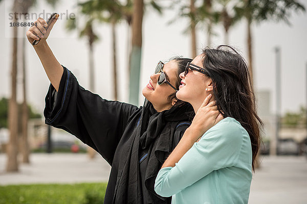 Junge Frau aus dem Nahen Osten in traditioneller Kleidung mit Smartphone-Selfie mit Freundin  Dubai  Vereinigte Arabische Emirate