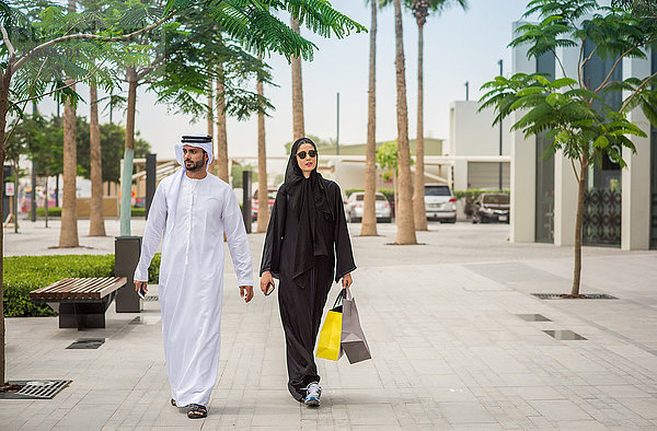 Einkaufspaar aus dem Nahen Osten in traditioneller Kleidung auf der Straße  Dubai  Vereinigte Arabische Emirate
