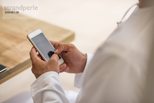 Nahaufnahme der Hände eines Mannes aus dem Nahen Osten mit einem Smartphone-Touchscreen in einem Café in Dubai  Vereinigte Arabische Emirate