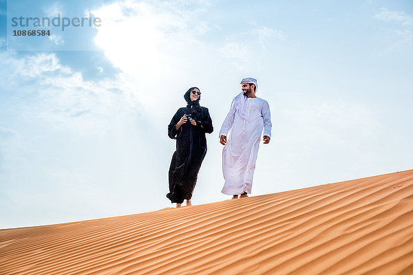 Paar in traditioneller nahöstlicher Kleidung auf Wüstendüne  Dubai  Vereinigte Arabische Emirate