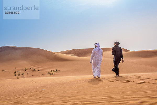 Paar in traditioneller nahöstlicher Kleidung zu Fuß in der Wüste  Dubai  Vereinigte Arabische Emirate