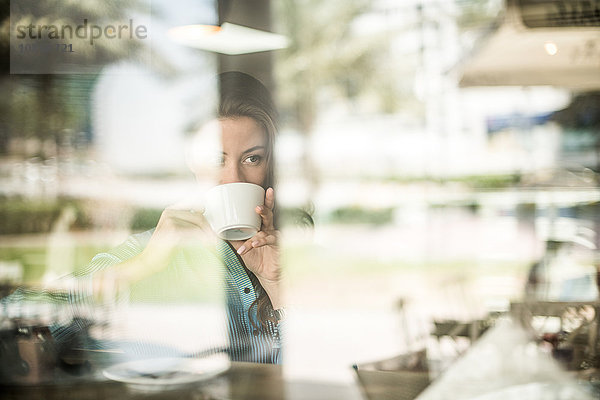 Frau trinkt Kaffee am reflektierenden Café-Fenster  Dubai  Vereinigte Arabische Emirate